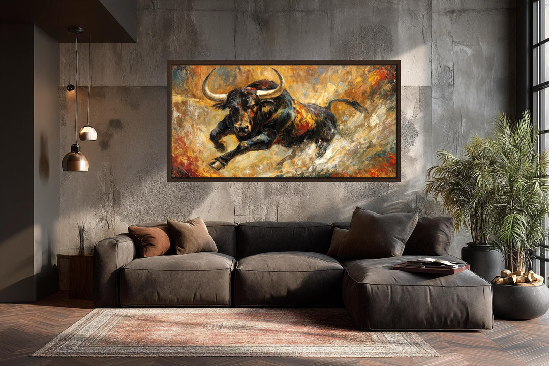 A framed canvas print of a charging black bull against a fiery gold and red abstract background.