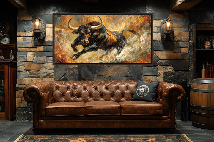 Charging bull canvas print in a bold abstract style with gold and red tones above a leather sofa.
