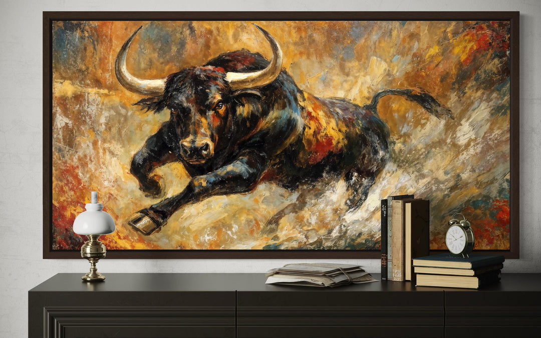Charging bull canvas wall art in a dark frame, featuring bold black, gold, and red abstract tones.