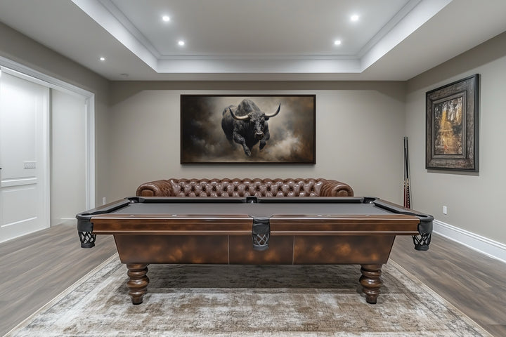 Framed canvas print of a charging bull hanging in a rustic man cave above a brown leather sofa.