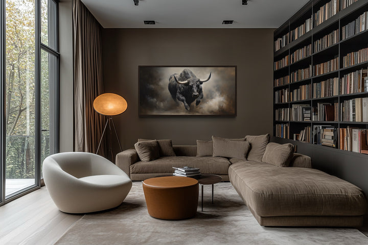 Framed charging bull canvas print on a dark wall in a modern living room with a brown sectional.