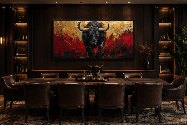 Framed canvas art of a charging black bull with red and gold abstract background in a dark office.