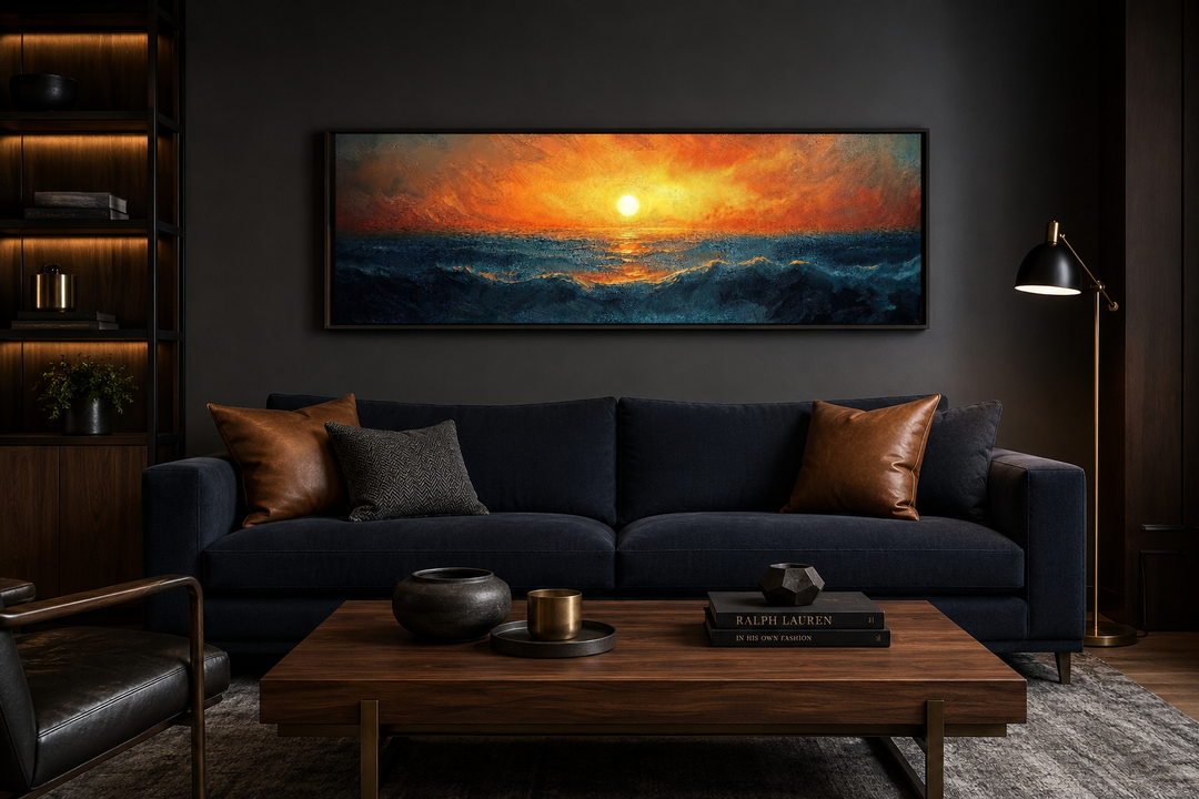 Ocean sunset long horizontal framed canvas wall art hanging above a dark blue sofa in a living room.