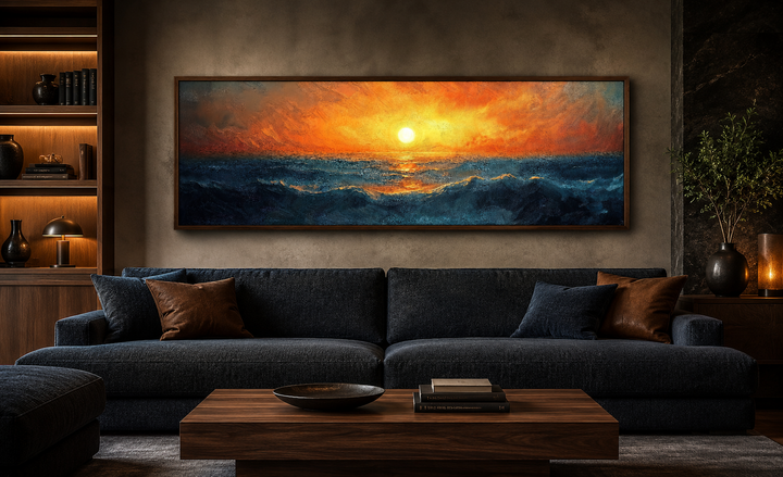 Long horizontal framed canvas wall art of an orange sunset over deep blue ocean waves above a sofa.
