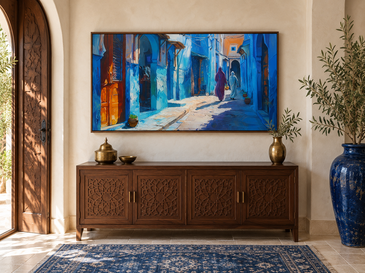 Chefchaouen blue street painting framed canvas wall art above a carved wooden sideboard.