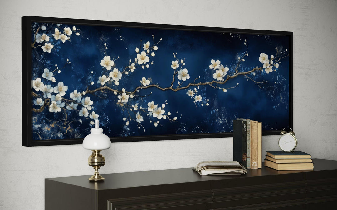 Panoramic cherry blossom canvas print with white flowers on a navy blue background in a black frame.