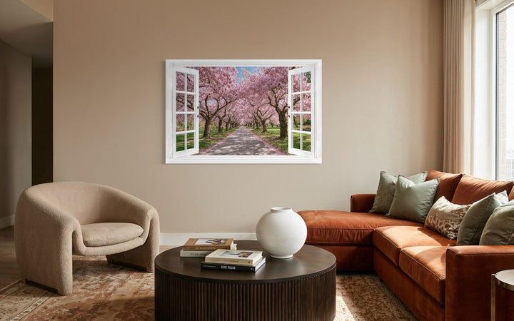 A window-view canvas print of a cherry blossom path hangs in a modern living room.