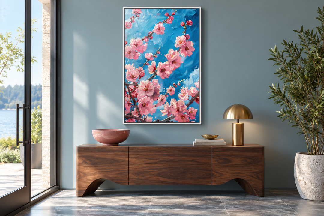 Framed canvas wall art of pink cherry blossom branches against a vibrant blue background.