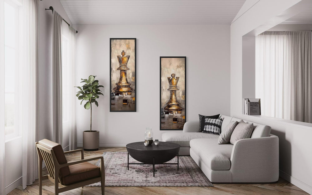 Two tall narrow canvas prints of a gold chess king and queen hanging in a modern living room.