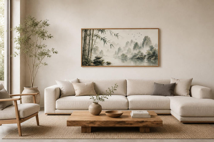 Chinese landscape canvas print of misty mountains and bamboo above a sofa in a zen living room.