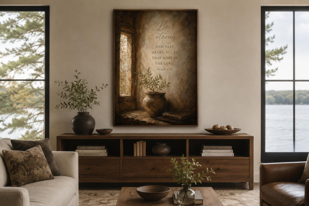 Be Strong Psalm 31:24 canvas wall art in a rustic frame above a wooden console in a living room.