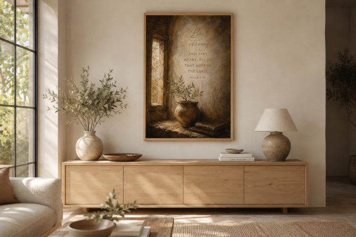 Be Strong Psalm 31 scripture wall art in a wooden frame above a light wood sideboard.