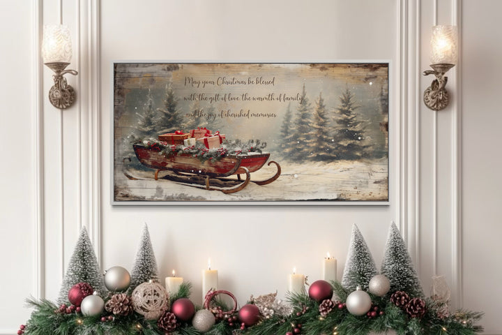 Framed canvas art of Santa's sleigh with gifts and a Christmas blessing above a decorated mantel.