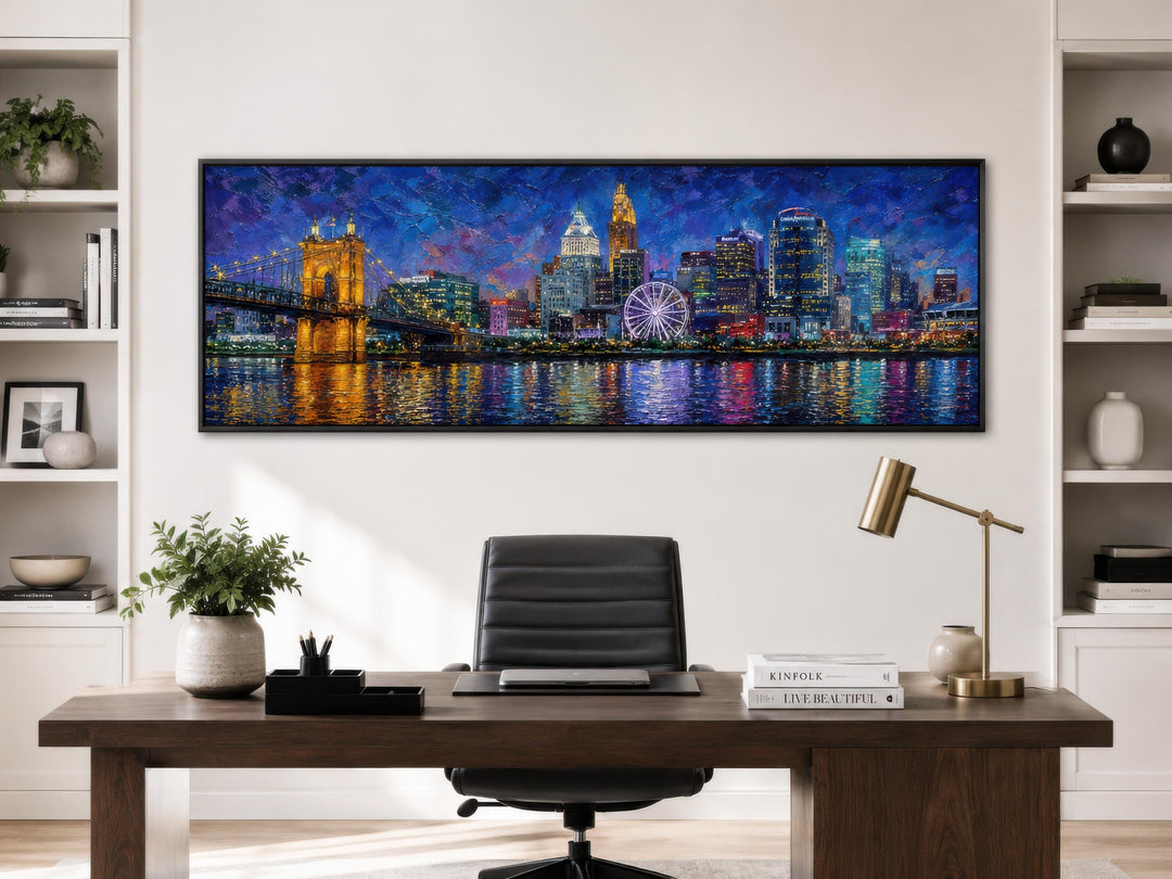 Panoramic Cincinnati skyline canvas print at night above a dark wood desk in a modern home office.