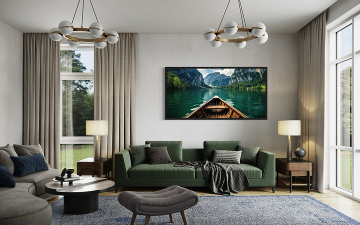 Framed canvas art of a wooden canoe on an emerald green lake hanging above a green sofa.