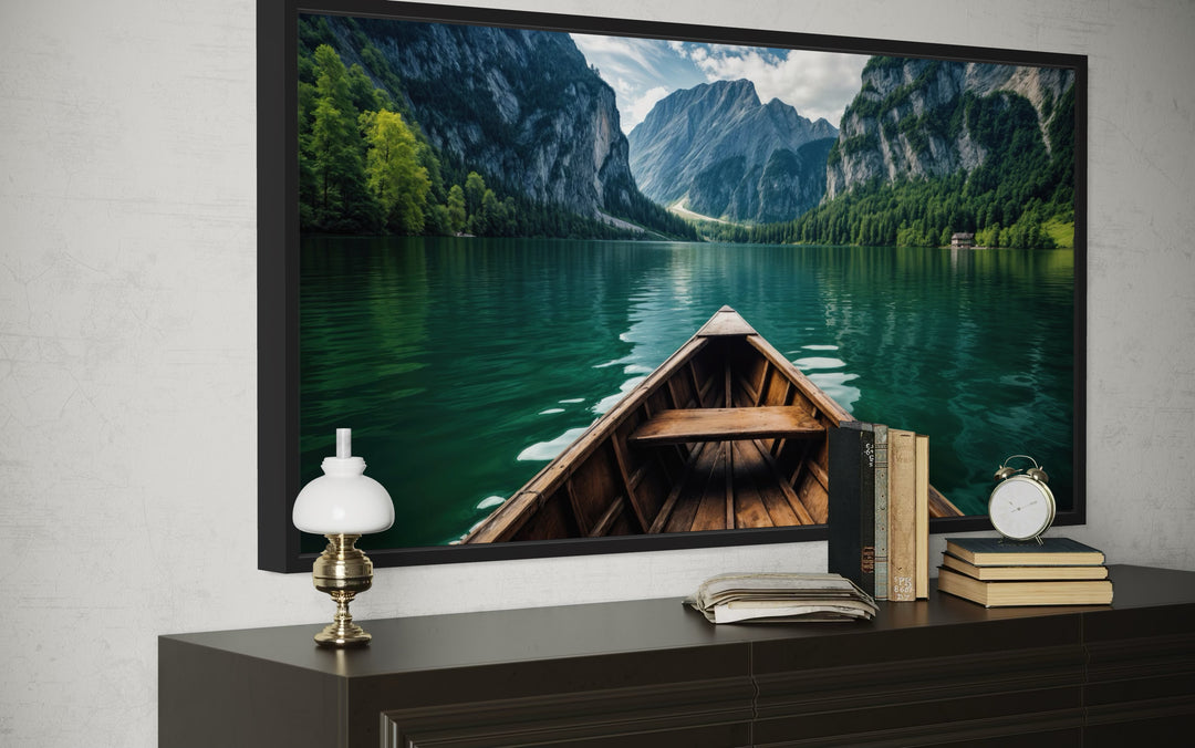 Framed canvas art of a wooden boat on an emerald green lake with mountains and forest.