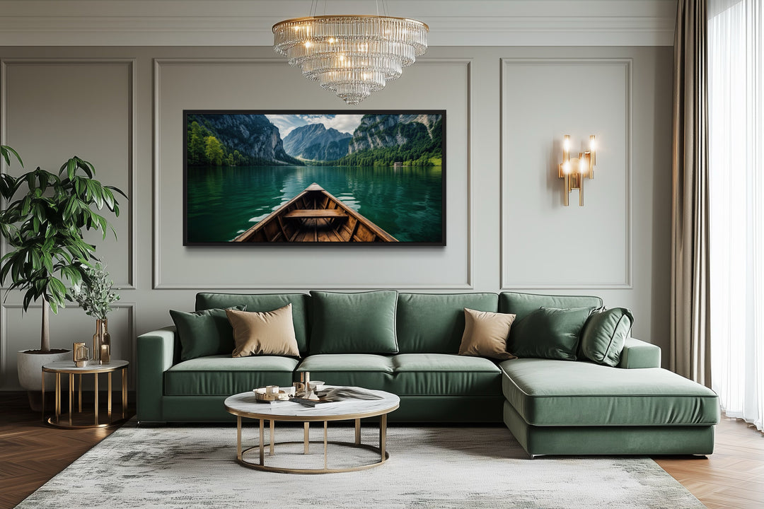 Framed canvas art of a wooden boat on an emerald green lake above a green sofa in a living room.