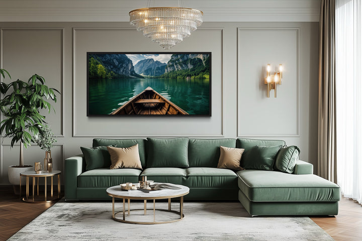 Framed canvas art of a wooden boat on an emerald green lake above a green sofa in a living room.