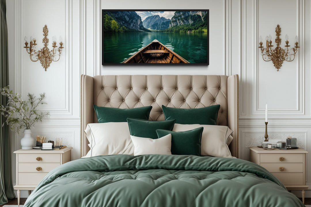 Framed canvas art of a wooden boat on an emerald green lake hanging above a tufted headboard.