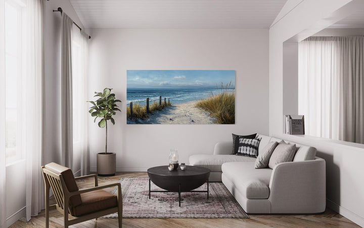 Horizontal canvas print of a coastal beach scene with blue and beige tones in a modern living room.