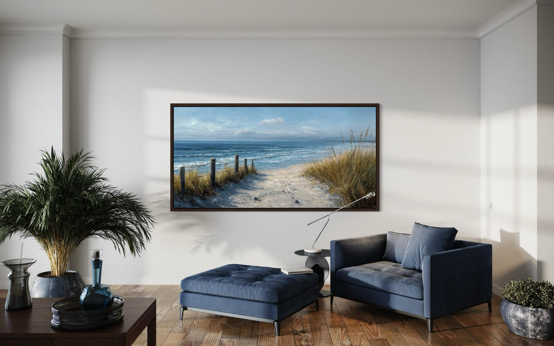 Horizontal canvas print of a coastal beach scene with blue and beige tones in a modern living room.