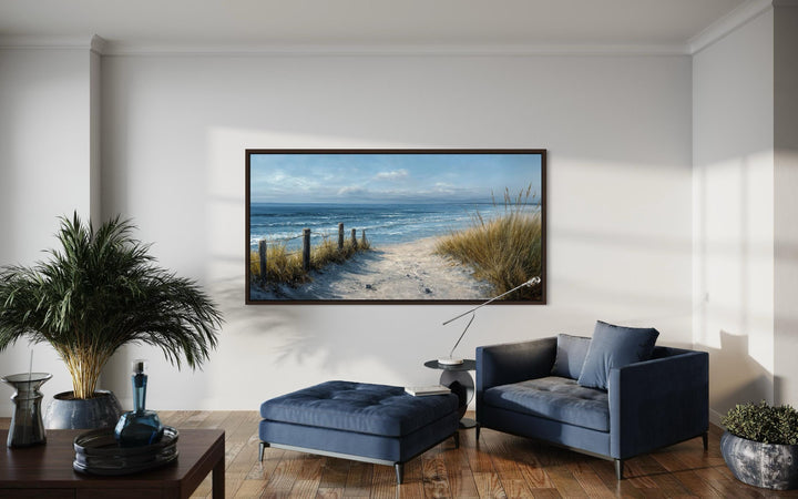 Horizontal canvas print of a coastal beach scene with blue and beige tones in a modern living room.