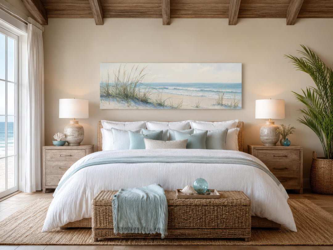 Coastal bedroom wall art featuring a sandy beach dunes ocean canvas print above a white bed.