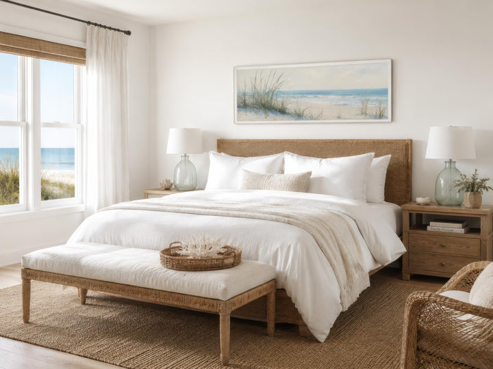 Coastal bedroom featuring a wide horizontal canvas print of sandy beach dunes above a woven bed.