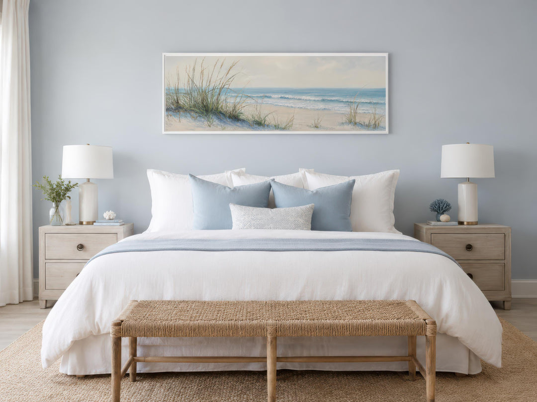 Coastal bedroom with a wide horizontal canvas print of sandy beach dunes and ocean above the bed.