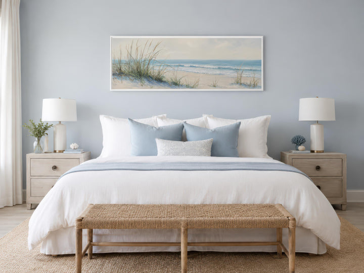 Coastal bedroom with a wide horizontal canvas print of sandy beach dunes and ocean above the bed.