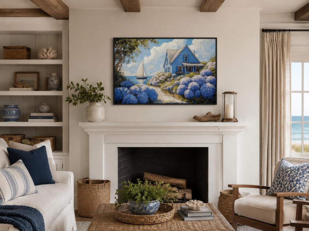 Coastal canvas print of a blue cottage and hydrangeas above a white fireplace in a living room.