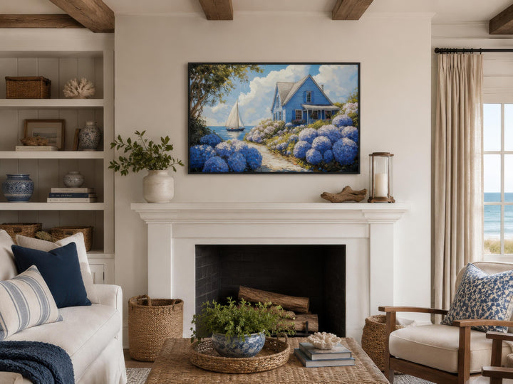 Coastal canvas print of a blue cottage and hydrangeas above a white fireplace in a living room.