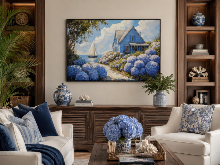 Coastal canvas print of a blue cottage and sailboat surrounded by blooming blue hydrangeas.
