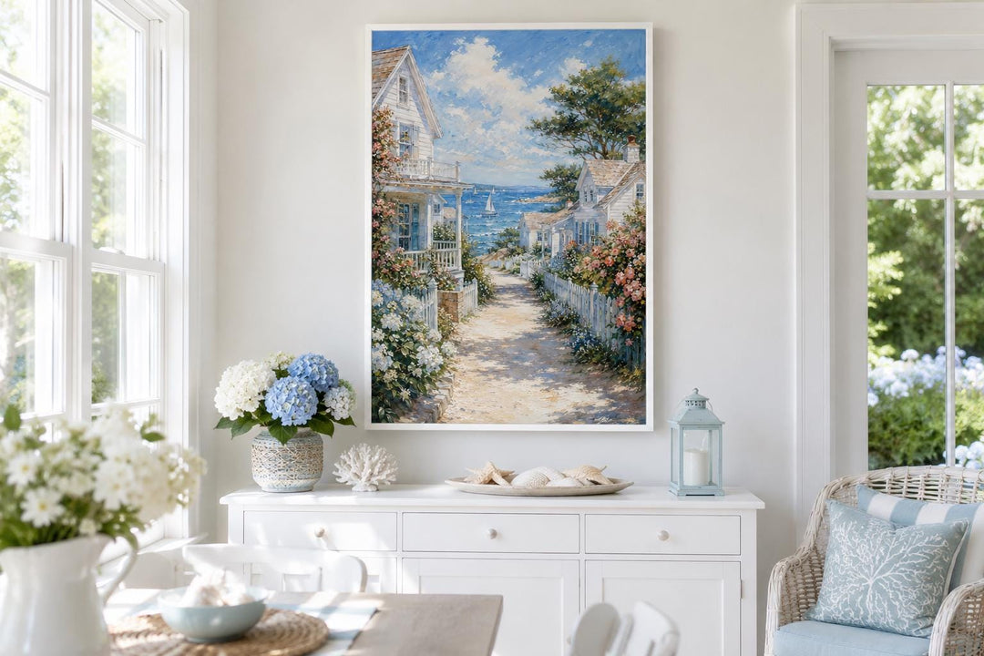 Vertical canvas print of a coastal cottage path leading to the sea, framed on a white wall.