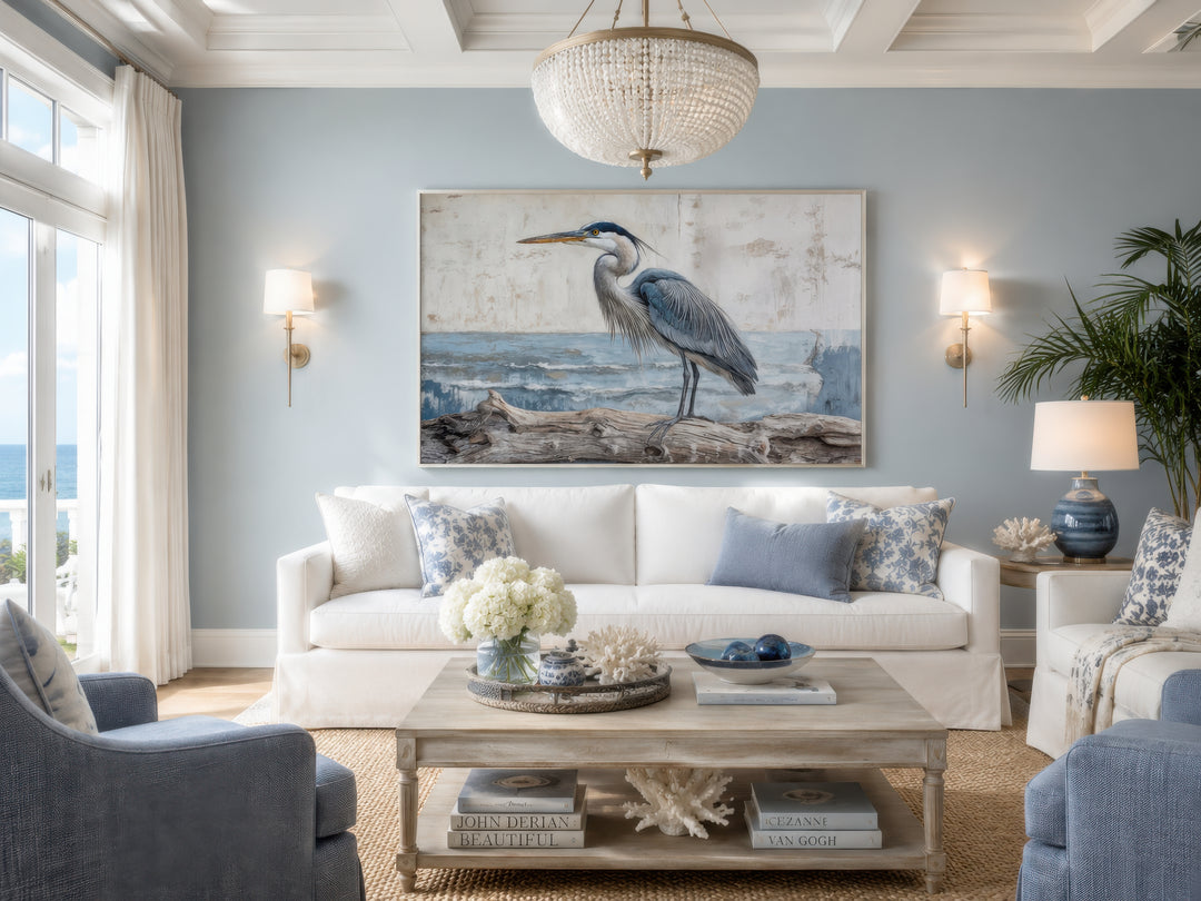 Coastal heron on driftwood canvas print wall art above a white sofa in a serene blue living room.