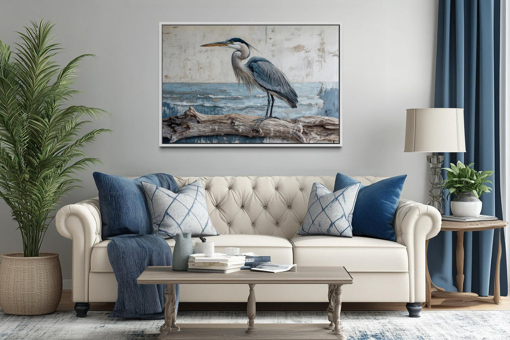 Coastal heron on driftwood canvas print hanging above a neutral sofa in a serene living room.