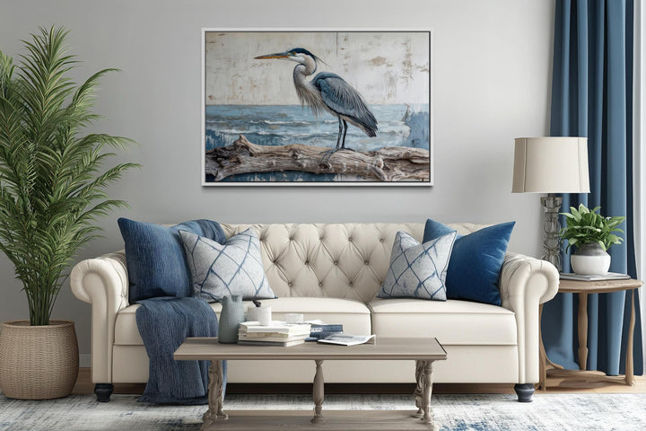 Coastal heron on driftwood canvas print hanging above a neutral sofa in a serene living room.