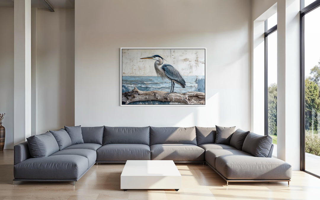 Coastal heron on driftwood canvas print displayed in a modern living room with a grey sectional.