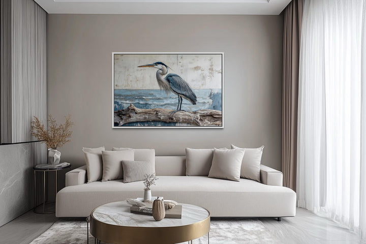 Coastal heron on driftwood canvas print above a neutral sofa in a serene, modern living room.