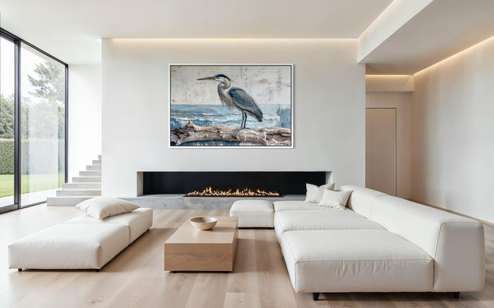 Coastal heron on driftwood canvas print above a modern fireplace in a minimalist living room.