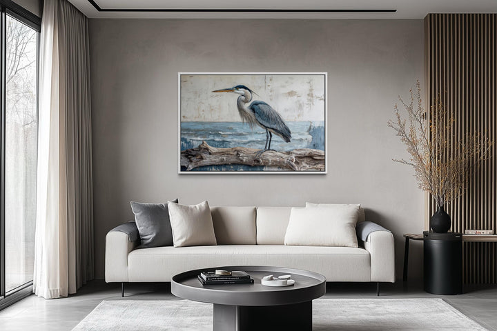 Coastal heron on driftwood canvas print wall art displayed above a modern sofa in a neutral room.