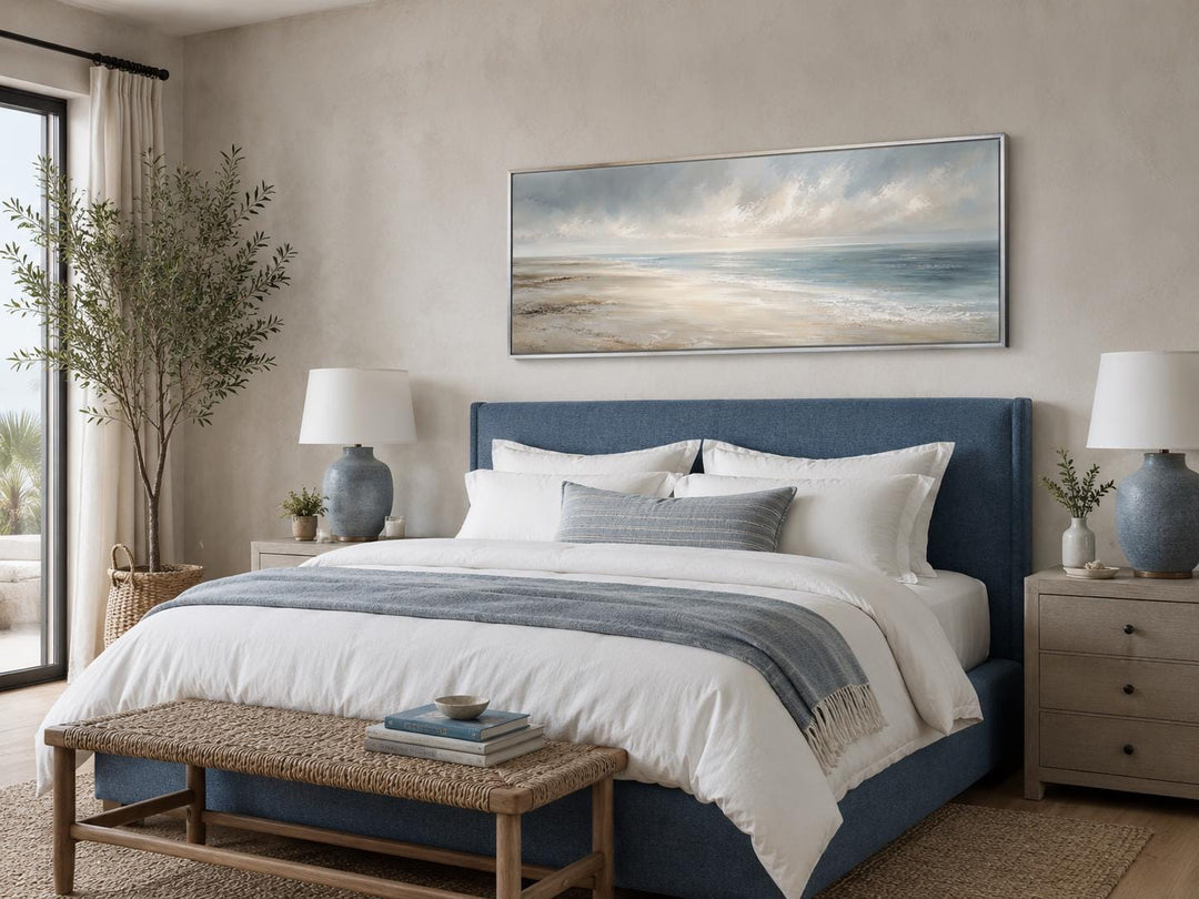 Long horizontal coastal wall art featuring a soft ocean seascape above a blue upholstered bed.