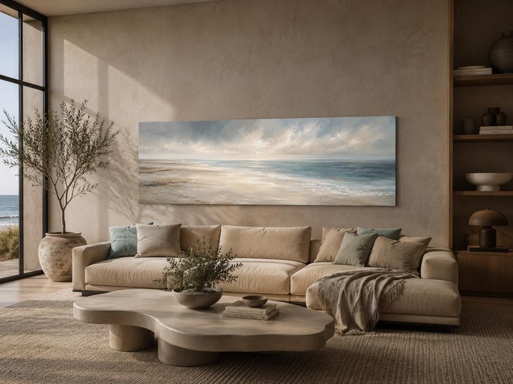 Long horizontal coastal wall art canvas featuring a soft ocean seascape above a neutral sofa.