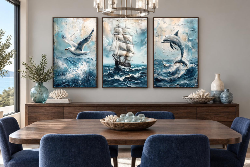 Set of 3 coastal canvas prints featuring a seagull, sailing ship, and dolphin over a dining table.