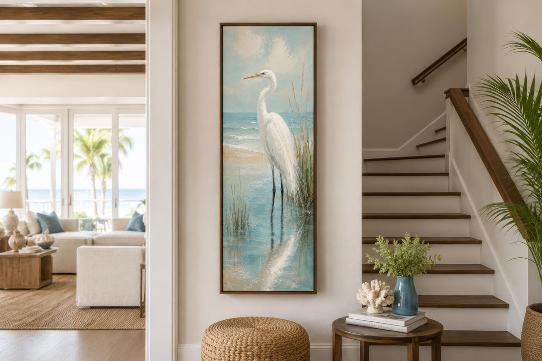 Tall narrow vertical canvas print of a white egret in teal coastal water on a beach house wall.
