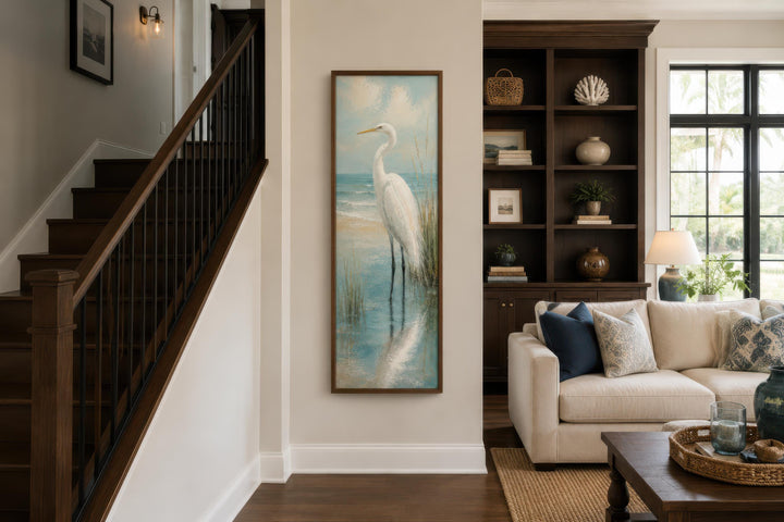 Tall narrow canvas print of a white egret in teal coastal water on a neutral living room wall.
