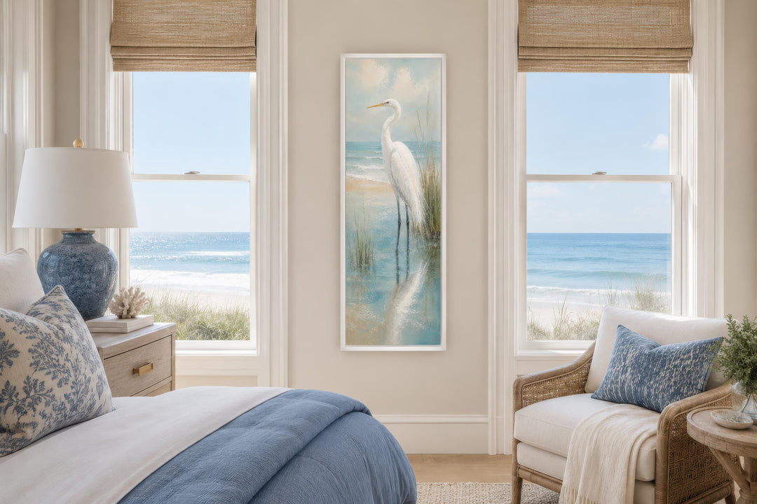 Tall narrow canvas print of a white egret in teal water hanging between two bedroom windows.
