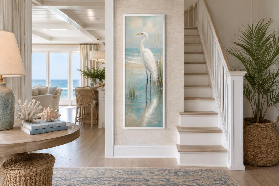 Tall narrow canvas print of a white egret in teal coastal water on a neutral textured wall.