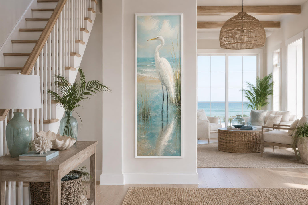 Tall narrow vertical canvas print of a white egret in teal coastal water on a beach house wall.