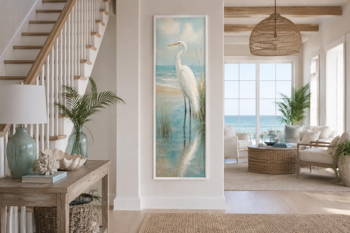 Tall narrow vertical canvas print of a white egret in teal coastal water on a beach house wall.